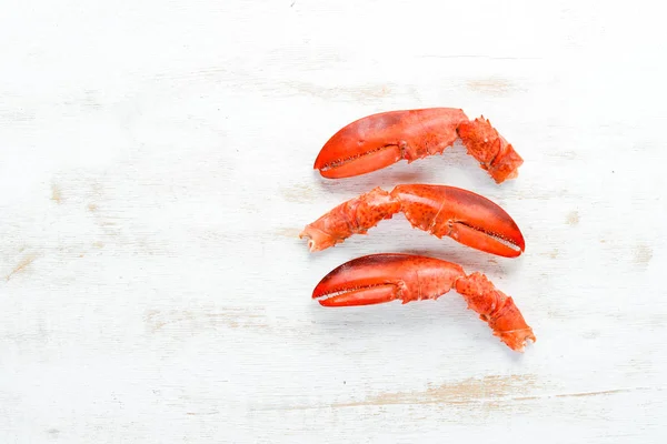 Lobster claws. Seafood on a white wooden background. Top view. Free copy space.