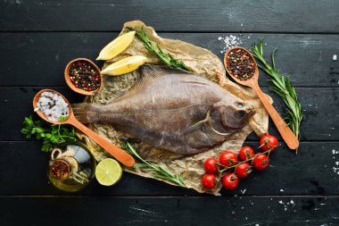 Baharat ile çiğ pisi balığı balık. Siyah taş arka planda deniz ürünleri. Üst görünüm. Ücretsiz kopya alanı.