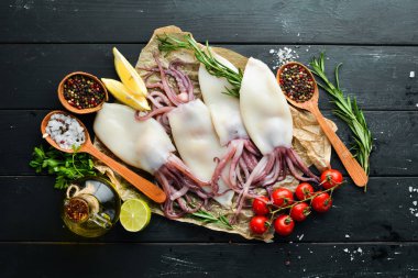 Baharat ile ham kalamar. Siyah taş arka planda deniz ürünleri. Üst görünüm. Ücretsiz kopya alanı.