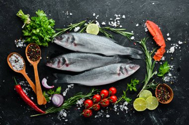 Deniz balığı Levrek. Siyah taş arka planda deniz ürünleri. Üst görünüm. Ücretsiz kopya alanı.