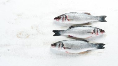 baharat ile balık levye. Beyaz ahşap arka planda deniz ürünleri. Üst görünüm. Ücretsiz kopya alanı.