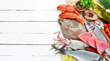Beyaz ahşap arka planda taze balık ve deniz ürünleri. Flounder, ıstakoz, kalamar, ton balığı, balık. Üst görünüm. Ücretsiz kopya alanı.