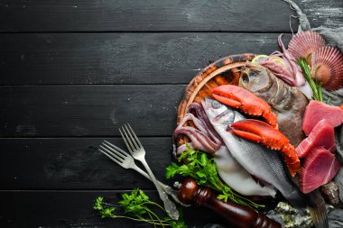 Siyah taş arka planda taze deniz ürünleri ve balık. Flounder, ıstakoz, kalamar, ton balığı, balık. Üst görünüm. Ücretsiz kopya alanı.