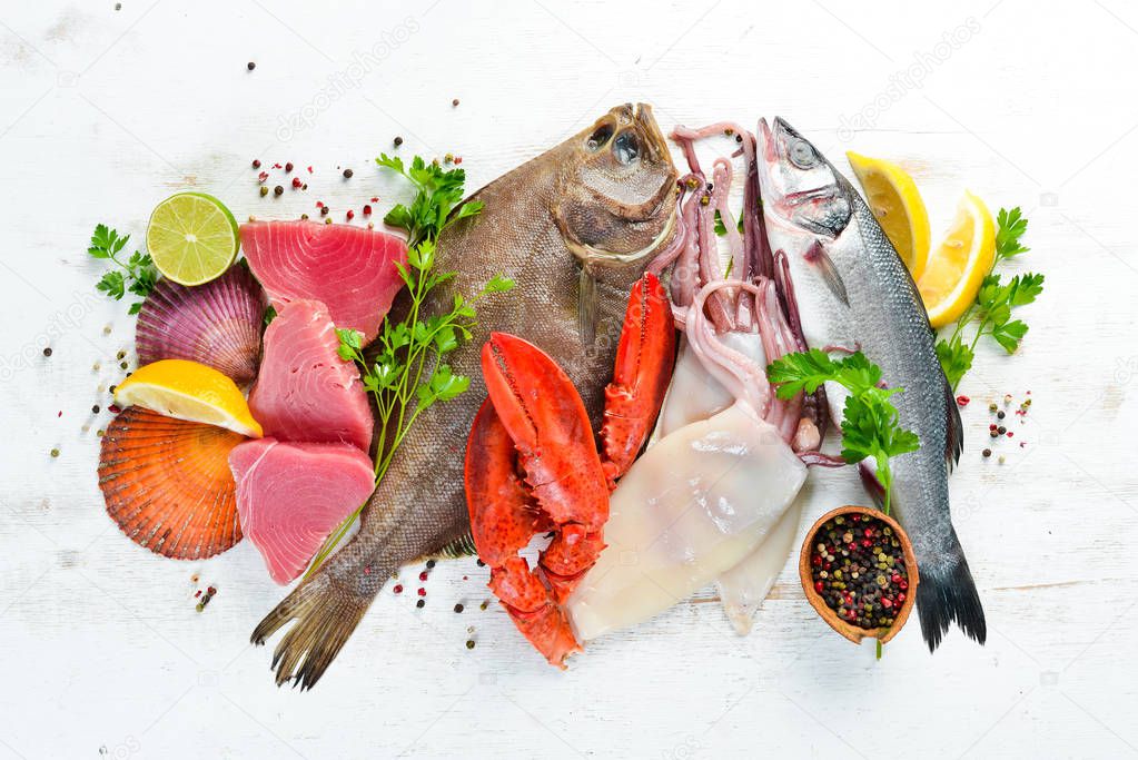 Fresh fish and seafood on a white wooden background. Flounder, lobster, squid, tuna, fish. Top view. Free copy space.
