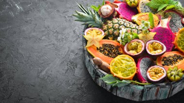 Tropikal meyveler: Papaya, mangosten, kaktüs meyve, pytahaya, siyah bir arka planda ananas. Üst görünüm. Metin için boş alan.