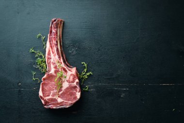 Siyah arka planda çiğ kuru biftek kovboy. Tomahawk bifteği. Barbekü üst görünümü. Metin için boş alan.