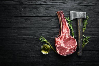Siyah arka planda çiğ kuru biftek kovboy. Tomahawk bifteği. Barbekü üst görünümü. Metin için boş alan.