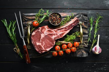 Siyah arka planda çiğ kuru biftek kovboy. Tomahawk bifteği. Barbekü üst görünümü. Metin için boş alan.