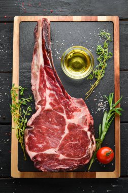 Siyah arka planda çiğ kuru biftek kovboy. Tomahawk bifteği. Barbekü üst görünümü. Metin için boş alan.