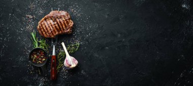 Çatal üzerinde ızgara ribeye biftek. Yaşlı masada. Üst görünüm. Metniniz için boş alan.