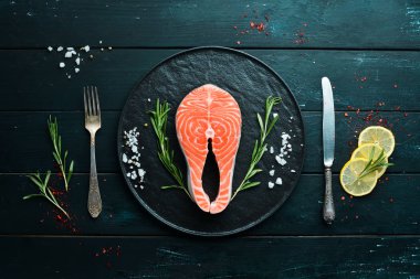 Siyah bir arka planda malzemeler ile çiğ somon biftek. Üst görünüm. Metniniz için boş alan.