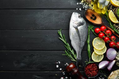 Siyah bir arka plan üzerinde limon ve baharat ile çiğ dorado balık. Üst te. Metniniz için boş alan.