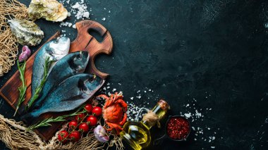 Siyah bir arka plan üzerinde limon ve baharat ile çiğ dorado balık. Üst te. Metniniz için boş alan.