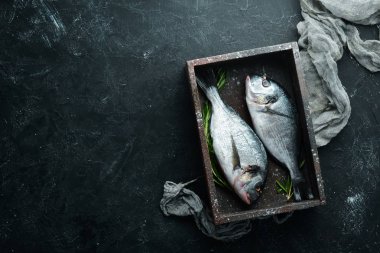 Siyah bir arka plan üzerinde limon ve baharat ile çiğ dorado balık. Üst te. Metniniz için boş alan.