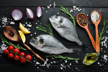 Siyah bir arka plan üzerinde limon ve baharat ile çiğ dorado balık. Üst te. Metniniz için boş alan.