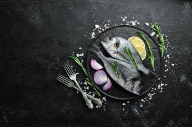 Siyah bir arka plan üzerinde limon ve baharat ile çiğ dorado balık. Üst te. Metniniz için boş alan.