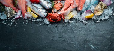 Seafood: Dorado, salmon, crab, grouper, oysters. On a black stone background. Top view. Free space for your text. clipart