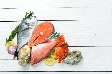 Beyaz ahşap arka plan üzerinde deniz ürünleri: Dorado, somon, yengeç, istiridye. Üst te. Metniniz için boş alan.