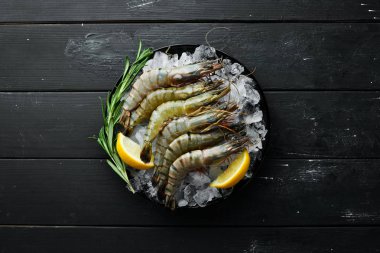 buz üzerinde limon ile siyah kaplan karides. Deniz ürünleri. Üst te. Siyah bir arka plan üzerinde. Ücretsiz kopyalama alanı.