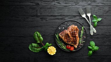 Biberiye ve baharatlar ile ızgara T-kemik biftek. Eski bir arka planda. Üst te. Ücretsiz kopyalama alanı.