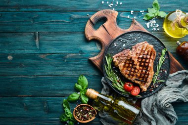 Biberiye ve baharatlar ile ızgara T-kemik biftek. Eski bir arka planda. Üst te. Ücretsiz kopyalama alanı.