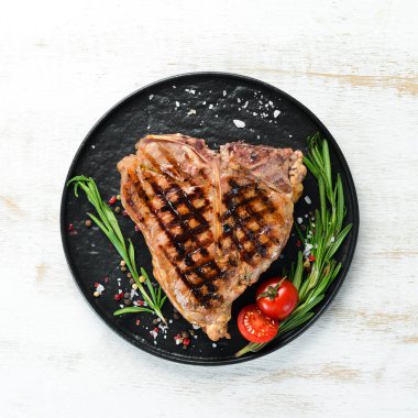 Biberiye ve baharatlar ile ızgara T-kemik biftek. Eski bir arka planda. Üst te. Ücretsiz kopyalama alanı.