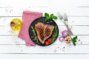 Biberiye ve baharatlar ile ızgara T-kemik biftek. Eski bir arka planda. Üst te. Ücretsiz kopyalama alanı.