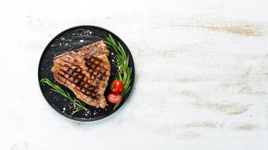 Biberiye ve baharatlar ile ızgara T-kemik biftek. Eski bir arka planda. Üst te. Ücretsiz kopyalama alanı.