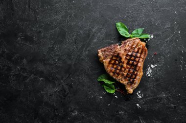 Biberiye ve baharatlar ile ızgara T-kemik biftek. Eski bir arka planda. Üst te. Ücretsiz kopyalama alanı.