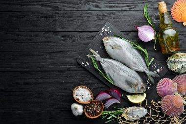 Limon, tuz ve biberiye ile çiğ deniz balığı. Siyah bir arka plan üzerinde. Üst te. Ücretsiz kopyalama alanı.