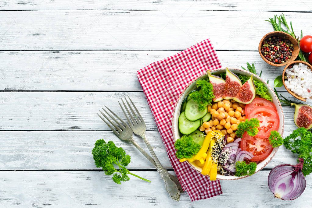 Healthy vegetable buddha bowl lunch with chickpeas, figs, cucumber, tomatoes and onions. Dishes menu. Free copy space. Top view.