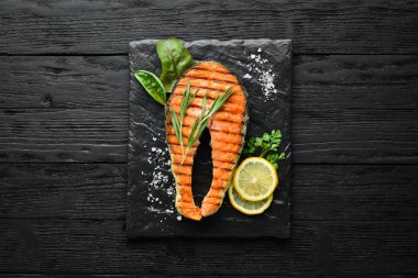 Taş tabakta ızgara somon bifteği. Eski bir arka planda. Üst te. Ücretsiz kopyalama alanı.