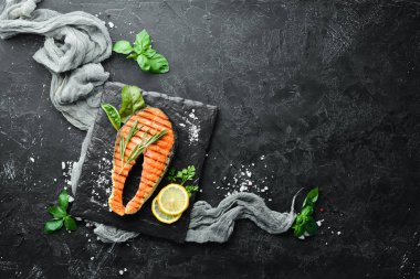 Taş tabakta ızgara somon bifteği. Eski bir arka planda. Üst te. Ücretsiz kopyalama alanı.