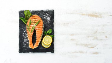 Taş tabakta ızgara somon bifteği. Eski bir arka planda. Üst te. Ücretsiz kopyalama alanı.