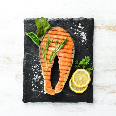 Taş tabakta ızgara somon bifteği. Eski bir arka planda. Üst te. Ücretsiz kopyalama alanı.