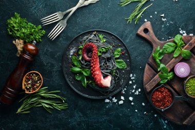 Ahtapot dokunaçlı siyah makarna. Taş tabakta deniz ürünleri. Eski arka planda. Üst te. Ücretsiz kopyalama alanı.