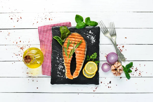 Grilled salmon steak on a stone plate. On an old background. Top view. Free copy space.