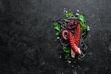 Ahtapot dokunaçlı siyah makarna. Taş tabakta deniz ürünleri. Eski arka planda. Üst te. Ücretsiz kopyalama alanı.