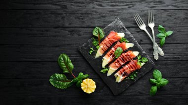 Prosciutto bir taş plaka üzerinde kavun ile. Geleneksel İtalyan mezesi. Üst te. Ücretsiz kopyalama alanı.