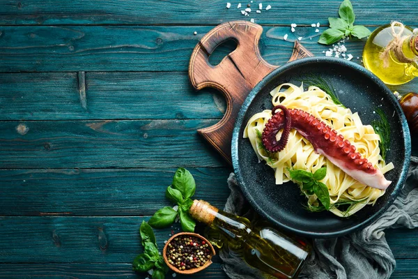 Pasta with octopus on a stone plate. Top view. Free copy space.