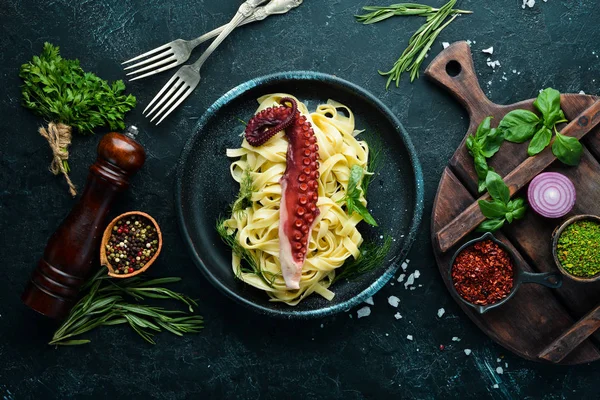 Pasta with octopus on a stone plate. Top view. Free copy space.