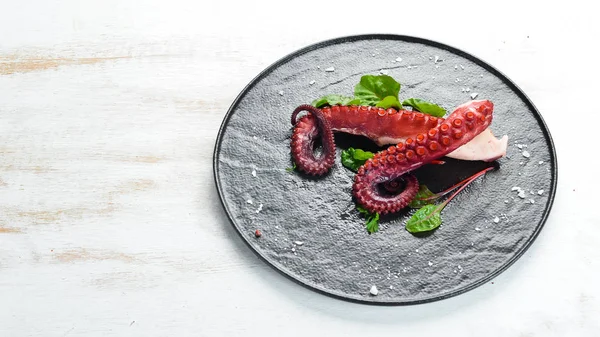 Boiled octopus tentacles on a stone plate. Seafood. Top view. Free copy space.