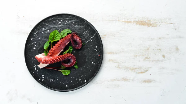 Boiled octopus tentacles on a stone plate. Seafood. Top view. Free copy space.