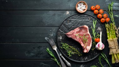 Tahta bir masada çiğ t-kemik biftek. Üst te. Metin için boş alan.