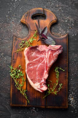 Tahta bir masada çiğ t-kemik biftek. Üst te. Metin için boş alan.
