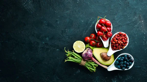Fresh vegetables and fruits on a black background. Vitamins and minerals. Top view. Free space for your text.