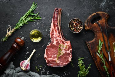 Siyah bir arka plan üzerinde çiğ kuru biftek tomahawk. Biftek Kovboyu. Barbekü. Üst te. Metin için boş alan.