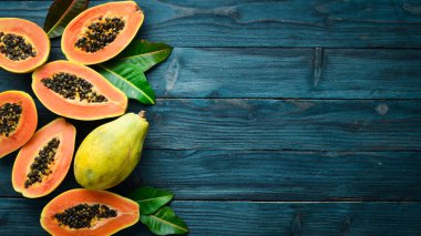 Tropikal meyveler, tatlı papaya, mavi ahşap arka plan üzerinde çiğ vegan gıda. Üst te. Metin için boş alan.
