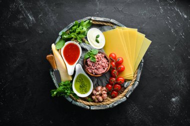 Lazanya hazırlanması için Malzemeler. Domates, sos, makarna. Siyah bir arka plan üzerinde. Üst te. Metniniz için boş alan.