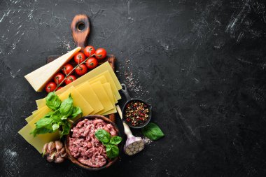 Lazanya hazırlanması için Malzemeler. Domates, sos, makarna. Siyah bir arka plan üzerinde. Üst te. Metniniz için boş alan.